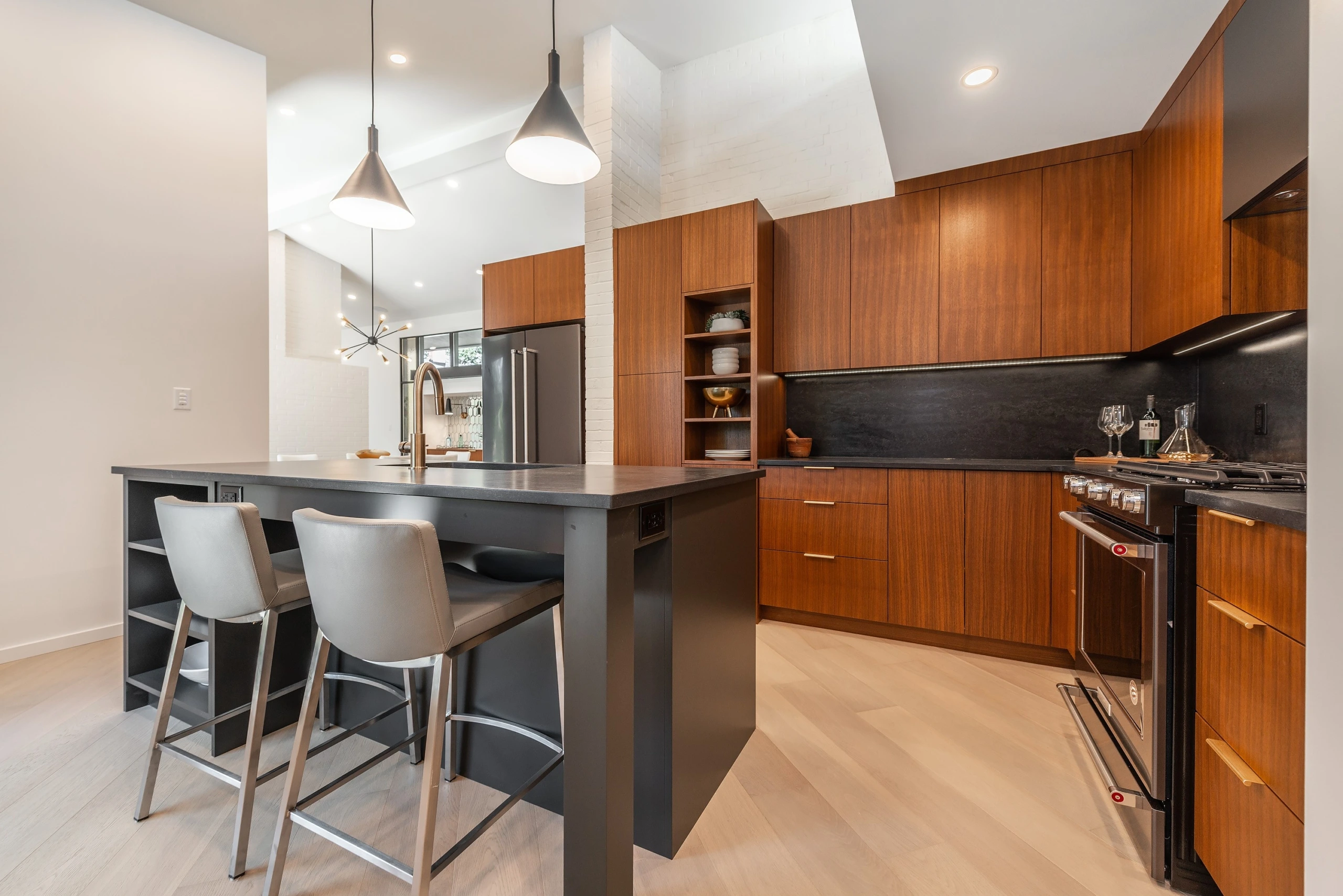 Contemporary kitchen featuring rich walnut cabinetry with dark island and integrated open shelving